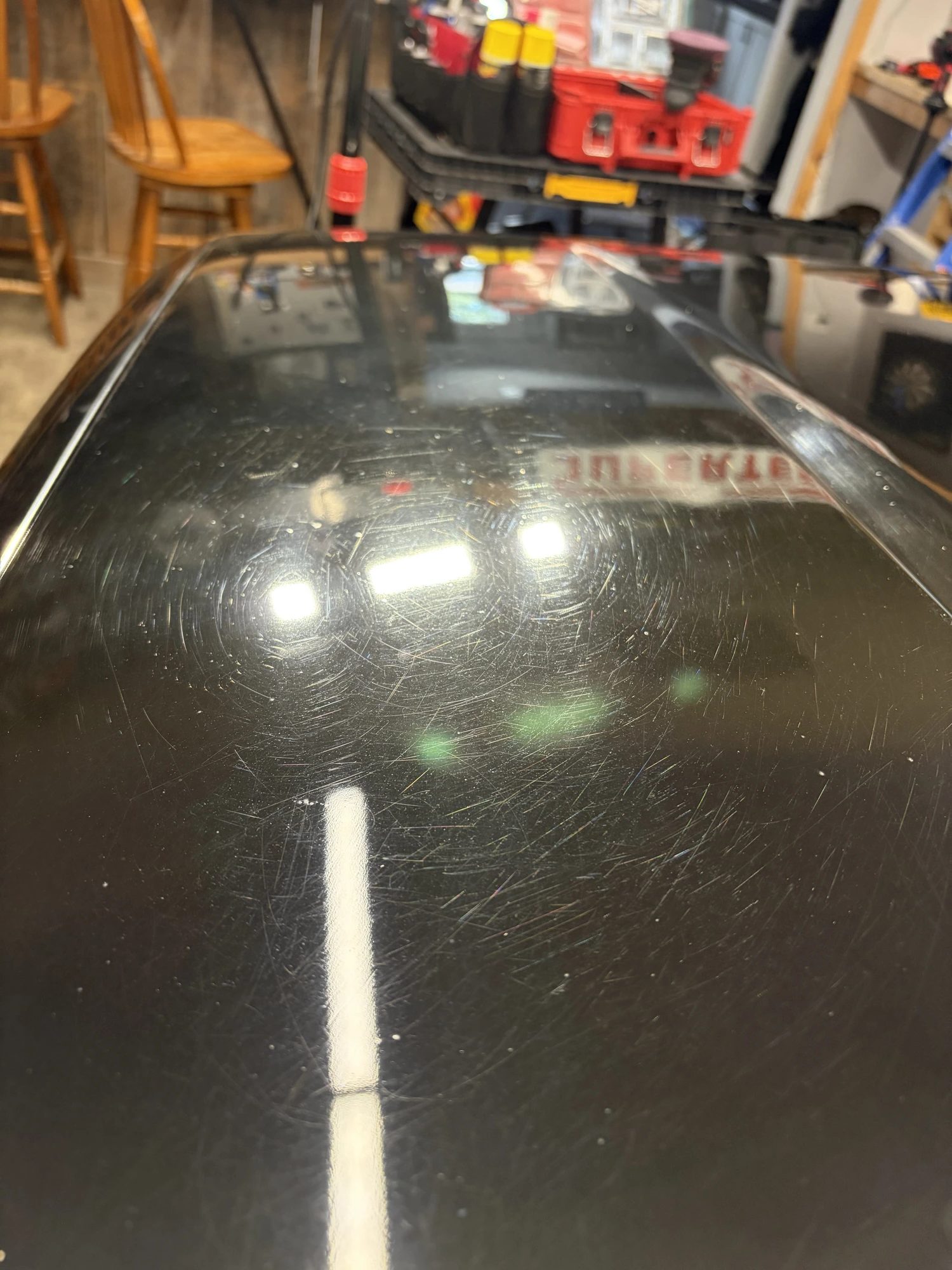 Black car paint before and after paint correction by Unreal Auto Spa — heavy swirl marks versus a corrected, glossy finish
